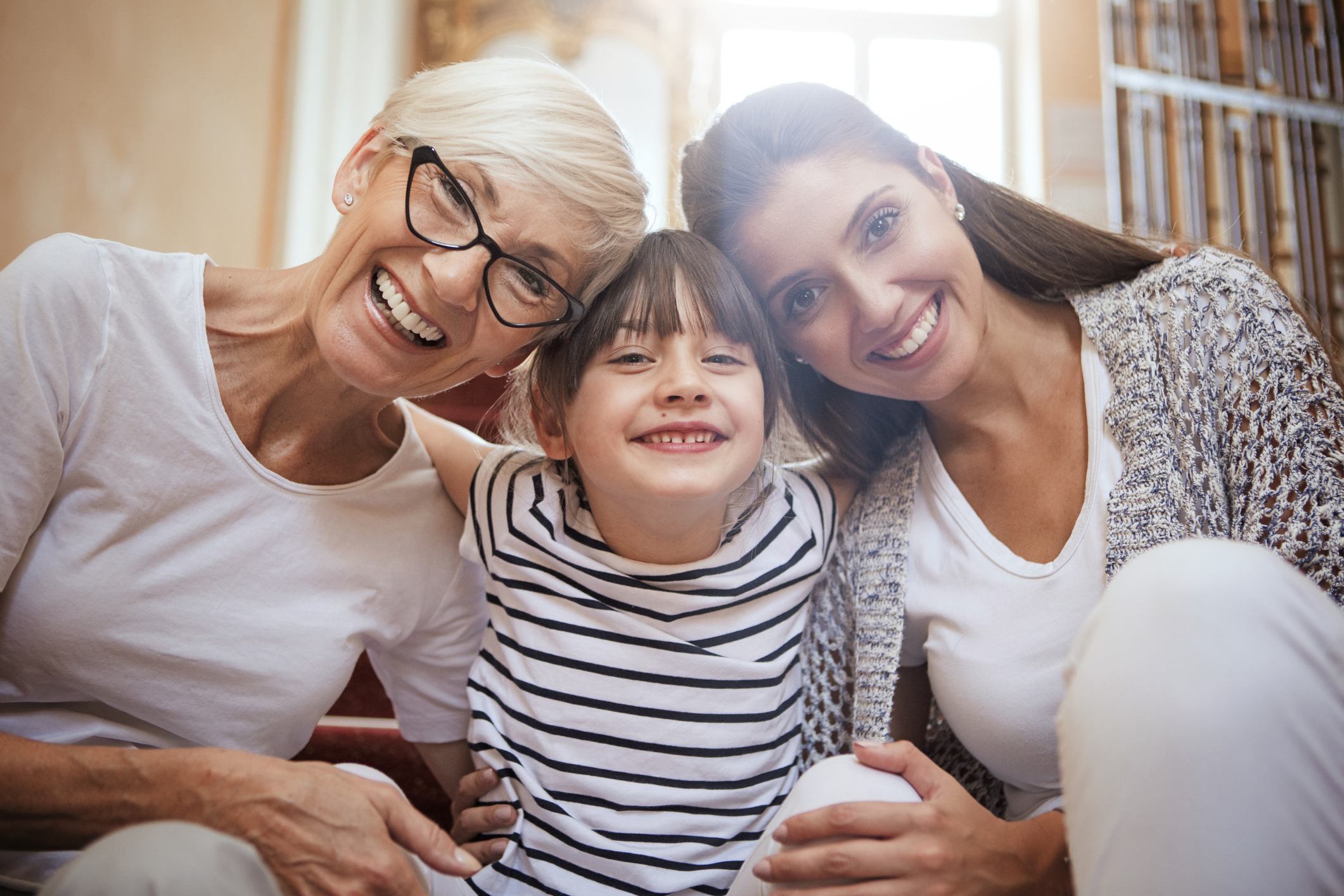 Portrait of girl hugging mom and grandmother smiling